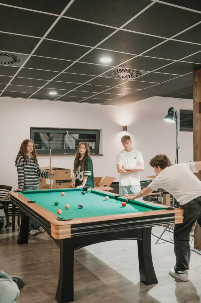 Mladí hrajú biliard po zhromaždení v Centre kresťanov Martin